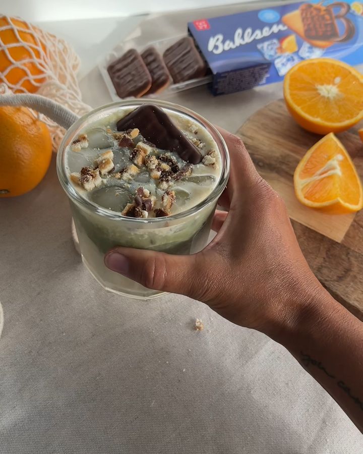 Matcha-Drink mit Bahlsen-Keks, Orangen im Hintergrund